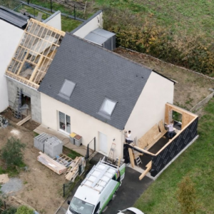 Chantier de rénovation avec extension en ossature bois à droite pour un garage et une extension en agglo à gauche pour une future chambre parentale