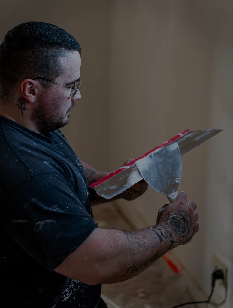 Professionnel du bâtiment appliquant de l’enduit lors de travaux de rénovation intérieure.