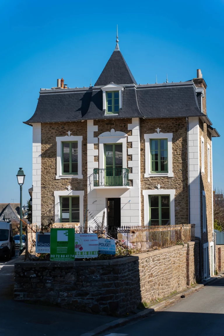 Façade rénovée d’une maison de caractère, avec pierre apparente, balcon et finitions soignées.