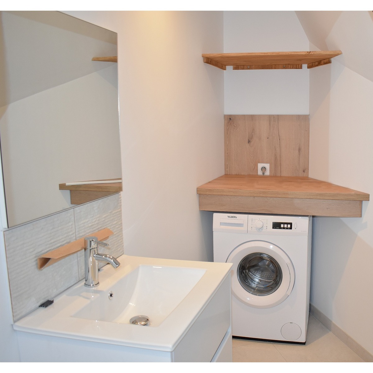 Aménagement rénové d’un espace buanderie avec plan de travail en bois et lavabo intégré.