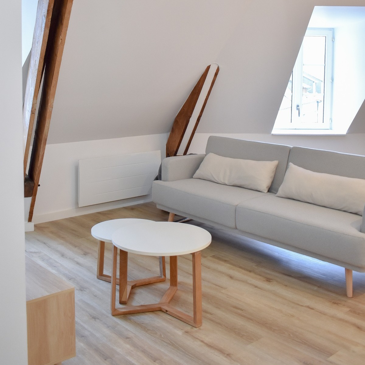 Espace salon lumineux aménagé sous pente avec fenêtre de toit.