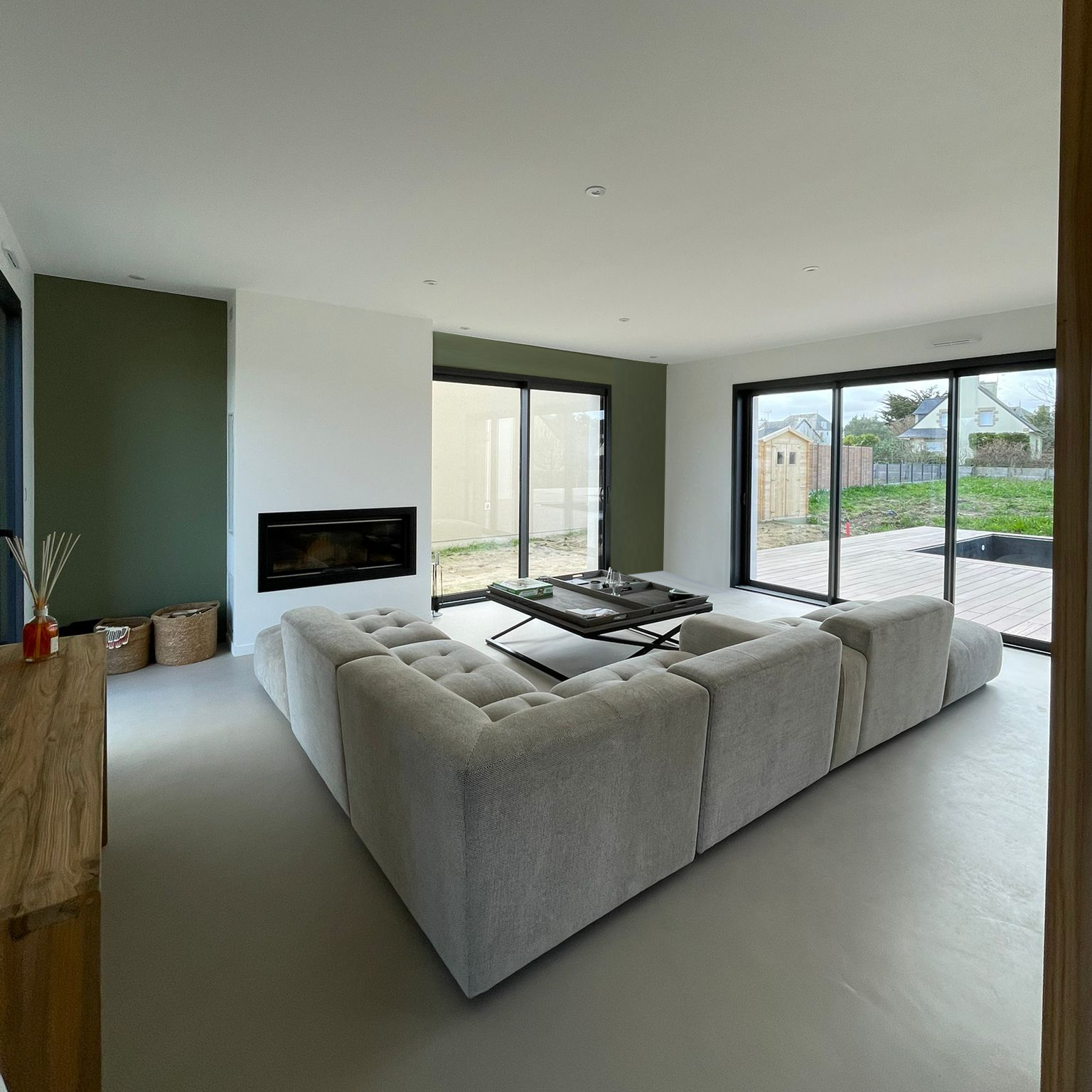 Pièce de vie rénovée avec salon contemporain, cheminée intégrée et larges ouvertures sur l’extérieur.