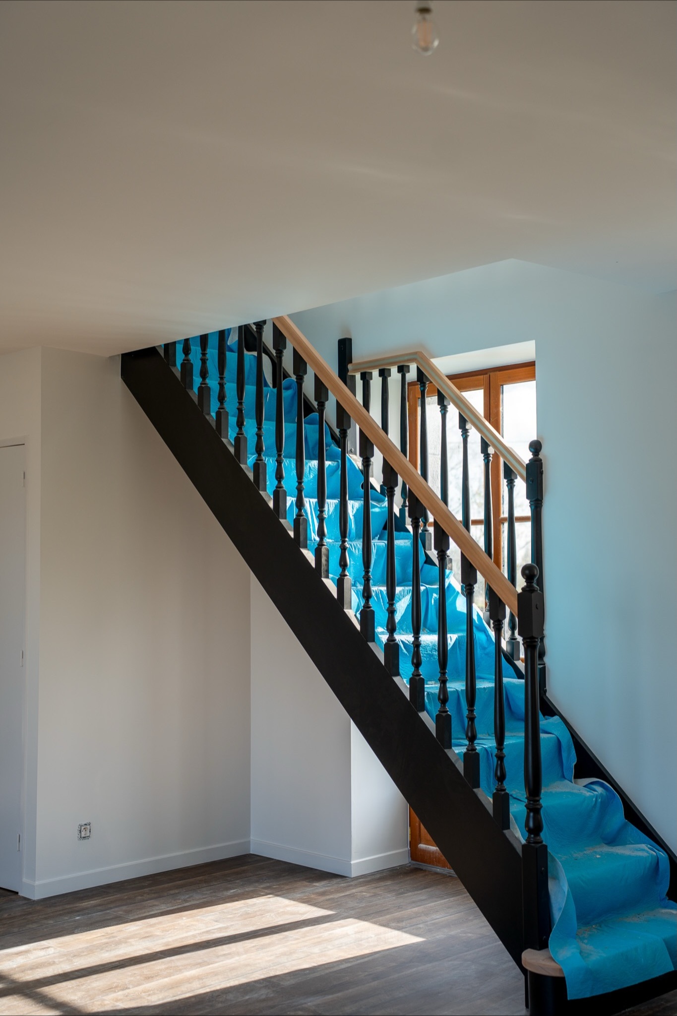 Escalier rénové dans une maison en travaux, avec sol neuf et finitions soignées.
