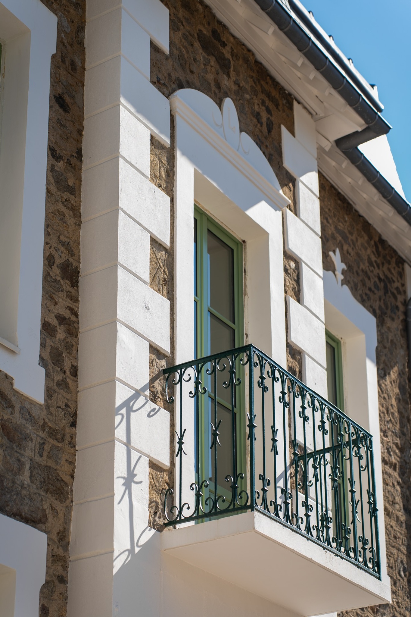 Rénovation de façade avec restauration des pierres, encadrements blancs et fenêtres rénovées.