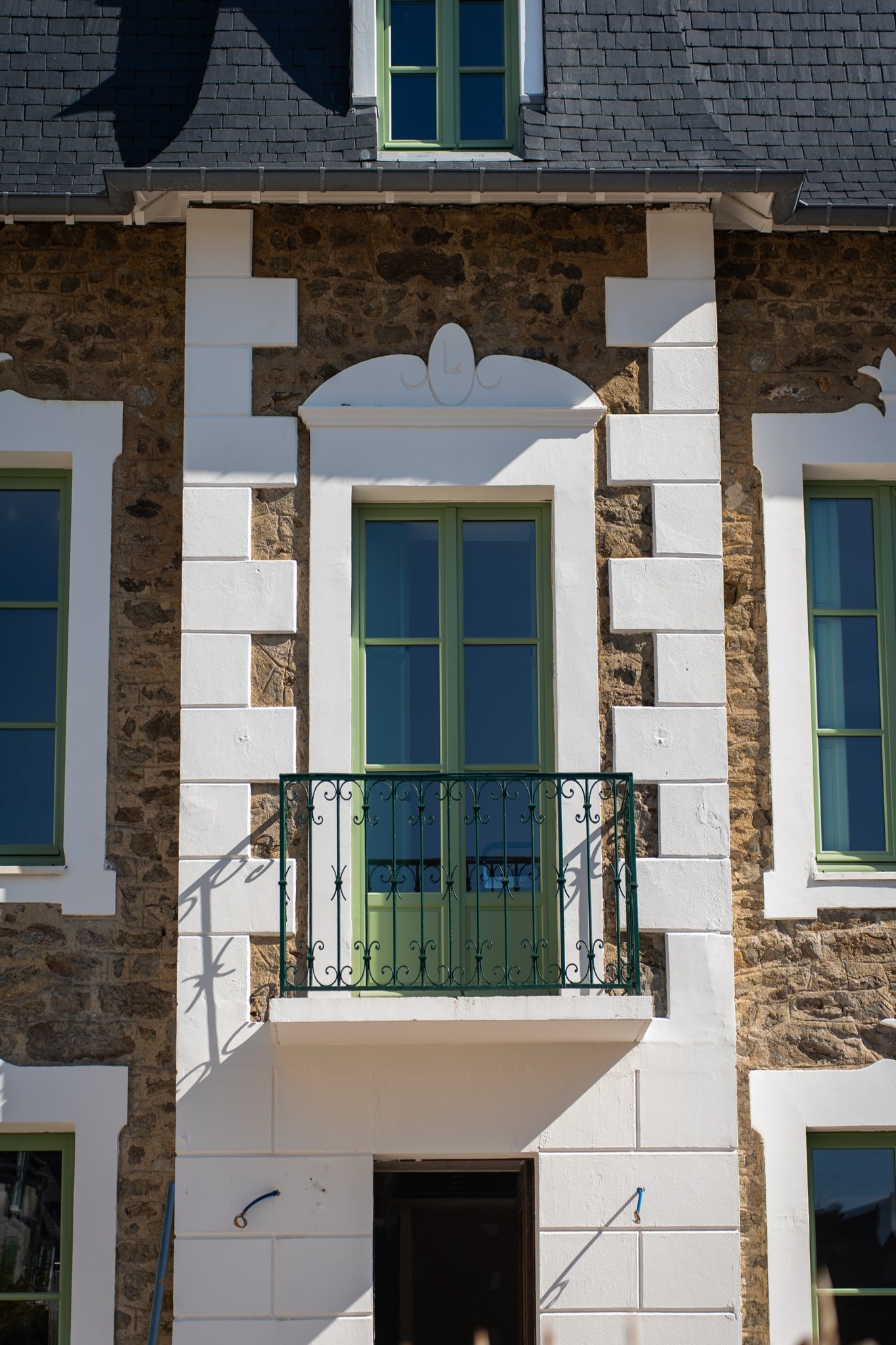 Rénovation de façade avec restauration des pierres, encadrements blancs et fenêtres rénovées.