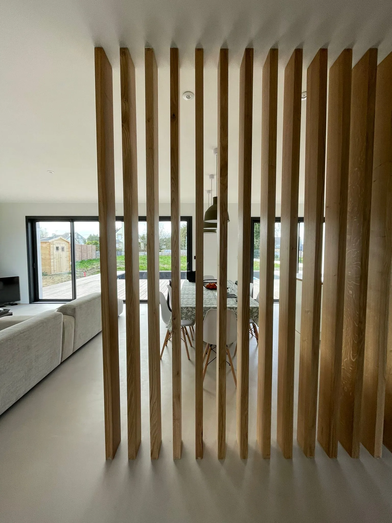 Aménagement intérieur rénové avec claustra en bois pour structurer un espace de vie ouvert
